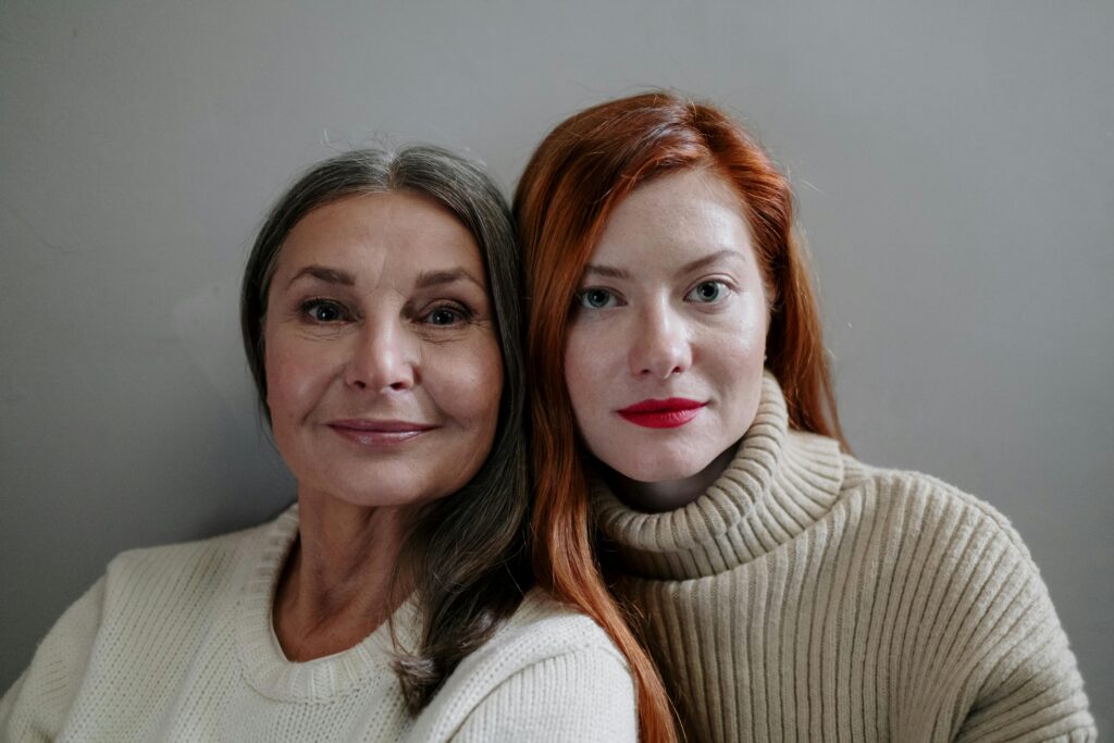 A touching portrait of a mother and daughter wearing knitted sweaters indoors.